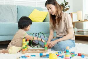 contento Asia madre giocare e imparare giocattolo blocchi con il poco ragazza. divertente famiglia è contento e eccitato nel il Casa. madre e figlia avendo divertimento la spesa tempo insieme. vacanza, attività, sviluppo foto