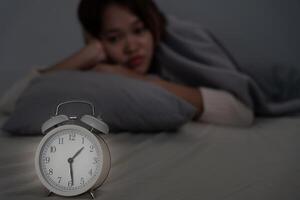 asiatico donna nel letto in ritardo provando per dormire sofferenza insonnia, insonne o impaurito nel un' incubo, guardare triste preoccupato e stressato. stanco e mal di testa o emicrania veglia su nel il mezzo di il notte. foto