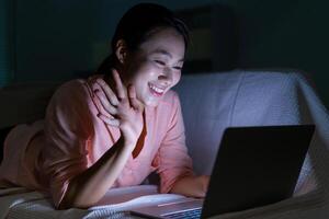 foto di giovane asiatico donna utilizzando il computer portatile nel il buio a mezzanotte