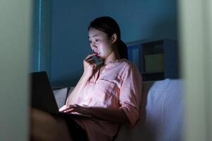 foto di giovane asiatico donna utilizzando il computer portatile nel il buio a mezzanotte