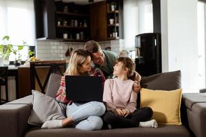 famiglia bonding tempo con il computer portatile nel accogliente casa ambientazione foto