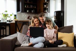 famiglia bonding tempo con il computer portatile nel accogliente casa ambientazione foto