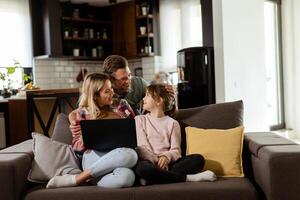 famiglia bonding tempo con il computer portatile nel accogliente casa ambientazione foto