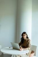 elegante professionale donna Lavorando su sua il computer portatile a un' moderno ufficio spazio foto