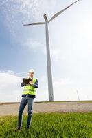ingegnere ispezionando vento turbina efficienza nel vasto verde campo su un' soleggiato giorno. foto