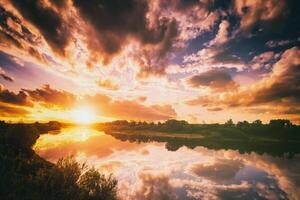 Alba o tramonto su un' lago o fiume con nuvoloso cielo riflessione nel il acqua nel estate. estetica di Vintage ▾ film. foto