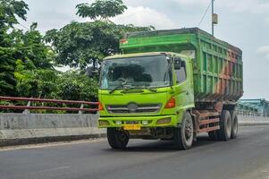 un hino cumulo di rifiuti camion passa al di sopra di un' calcestruzzo autostrada ponte, Indonesia, 16 gennaio 2024. foto