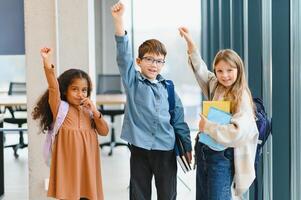 ritratto di sorridente poco scuola bambini nel scuola corridoio foto