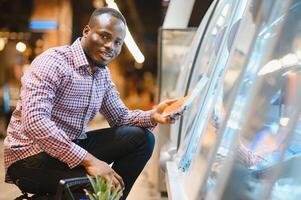 attraente africano americano uomo shopping nel un' supermercato foto