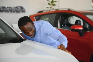 bello uomo è in piedi vicino il suo nuovo auto e sorridente foto