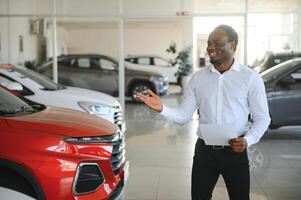 macchine concessionaria concetto. auto venditore afro uomo in piedi nel automobile centro foto