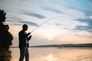 pesca. Filatura a tramonto. silhouette di un' pescatore foto