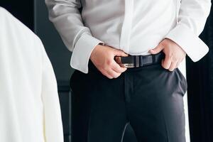 un' uomo nel nero pantaloni e un' bianca camicia abbottonato un' Marrone pelle pantaloni cintura. attività commerciale uomo. foto