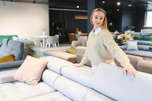 contento giovane donna sceglie divano per casa nel mobilia memorizzare foto