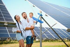 il concetto di verde energia. contento famiglia a piedi e avendo divertimento nel solare pannello campo. verde energia. foto