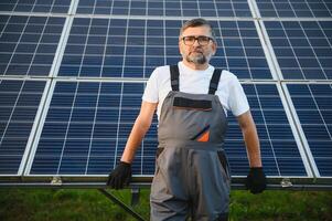 ritratto di anziano lavoratore nel uniforme in piedi vicino solare pannelli foto