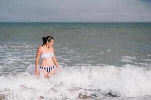 bellissimo ragazza con bella gambe a piedi lungo il riva del mare nel il estate caldo giorno vicino il mare. foto