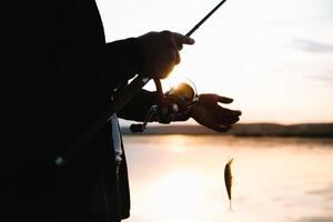 il del pescatore mani, detiene il Filatura asta, ruota il bobina maneggiare. passatempo e attività. foto