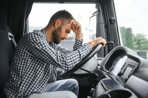 uomo camionista stanco guida nel un' cabina di il suo camion foto