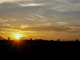 spettacolare tramonto Sopra, arancia sole crescente su al di sopra di il orizzonte foto