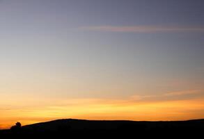 spettacolare tramonto Sopra, arancia sole crescente su al di sopra di il orizzonte foto