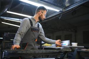 uomo Lavorando nel stampa Casa con carta e vernici foto