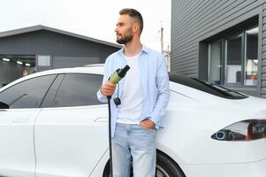 uomo ricarica elettrico auto di il Casa. foto