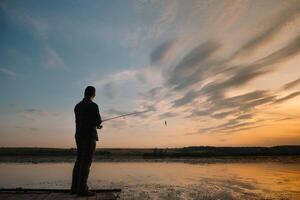 pesca. Filatura a tramonto. silhouette di un' pescatore. foto