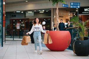 Al dettaglio, gesto e vendita concetto - sorridente adolescenziale ragazza con molti shopping borse a centro commerciale. foto