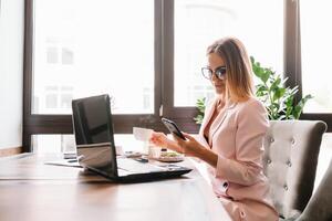 attività commerciale donna su il Telefono a ufficio. giovane attività commerciale donna avendo Telefono chiamata a il ufficio. sorridente attività commerciale donna. bella giovane attività commerciale utilizzando smartphone a il soffitta ufficio. foto