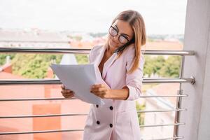 attività commerciale donna su il Telefono a ufficio. giovane attività commerciale donna avendo Telefono chiamata a il ufficio. sorridente attività commerciale donna. bella giovane attività commerciale utilizzando smartphone a il soffitta ufficio. foto