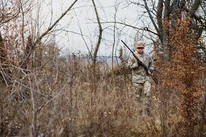 a caccia, guerra, esercito e persone concetto - giovane soldato, guardia forestale o cacciatore con pistola a piedi nel foresta. foto