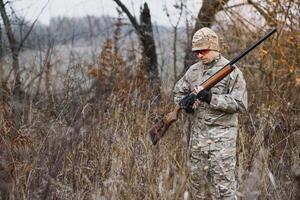 a caccia permesso. uomo brutale guardiacaccia natura sfondo. cacciatore trascorrere tempo libero a caccia. cacciatore hold riffle. messa a fuoco e concentrazione di esperto cacciatore. a caccia e intrappolamento le stagioni. foto