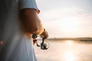 il del pescatore mani, detiene il Filatura asta, ruota il bobina maneggiare. passatempo e attività. foto