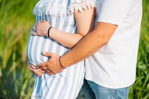 Immagine di incinta coppia. marito toccante il suo moglie pancia con mani. incinta donna all'aperto. foto