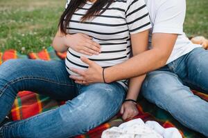 Immagine di incinta coppia. marito toccante il suo moglie pancia con mani. incinta donna all'aperto. foto