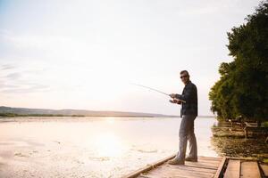 giovane uomo pesca a nebbioso Alba. foto