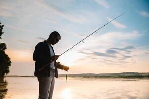 pescatore uomo pesca con Filatura asta su un' fiume banca a nebbioso nebbioso Alba. pescatore con Filatura. Filatura concetto. foto