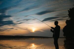 pesca. Filatura a tramonto. silhouette di un' pescatore. foto