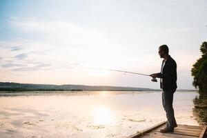 giovane uomo pesca a nebbioso Alba. foto
