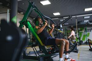 atletico giovane nero uomo avendo allenarsi su il petto stampa macchina nel Palestra foto