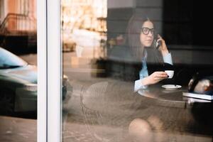 giovane donna d'affari parlando su il Telefono nel caffè negozio foto