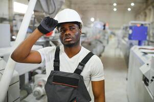 industriale lavoratore in casa nel fabbrica. giovane tecnico con bianca difficile cappello foto
