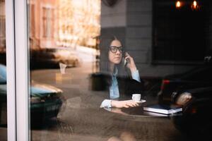 giovane donna d'affari parlando su il Telefono nel caffè negozio foto