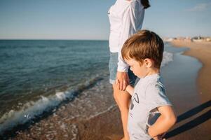 madre e figlio giocando su il spiaggia a il tramonto volta. concetto di amichevole famiglia foto