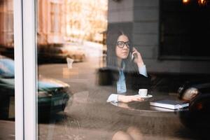 giovane donna d'affari parlando su il Telefono nel caffè negozio foto