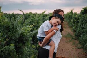 bellissimo giovane sorridente famiglia ragazzo e madre avendo divertimento a un' vigneto foto