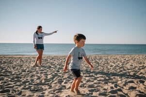 madre e figlio giocando su il spiaggia a il tramonto volta. concetto di amichevole famiglia foto