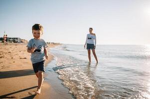 madre e figlio giocando su il spiaggia a il tramonto volta. concetto di amichevole famiglia foto