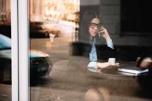 giovane donna d'affari parlando su il Telefono nel caffè negozio foto